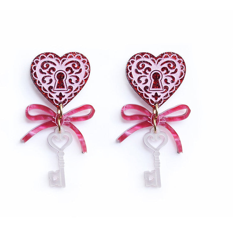 Heart-shaped earrings with key designs and pink ribbons on a white background