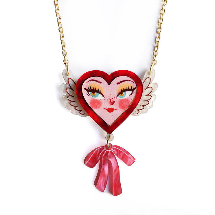 Heart-shaped pendant with a face design on a gold chain against a white background