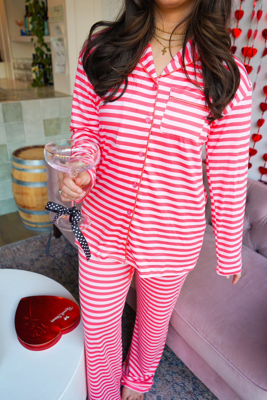 Person wearing red and white striped pajamas holding a glass in a living room.
