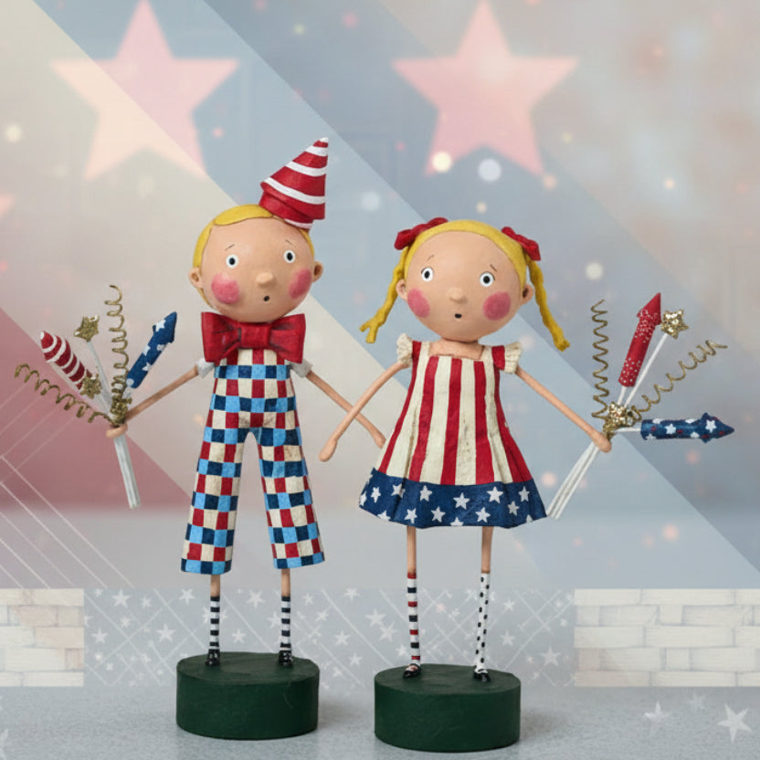 Two decorative figures, a boy and a girl, in patriotic outfits with sparklers on a light background.