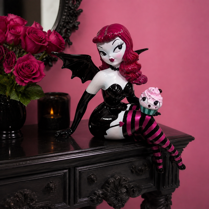 Meet Verna Bat Girl, one of the showstoppers from the newest Miss Fluff x December Diamonds collection. Standing an incredible 27.5 inches tall, she’s equal parts spooky, glamorous, and delightfully whimsical.

From her dramatic bat wings and vintage pin-up style to her striped stockings and mischievous cupcake companion, every inch is packed with the signature details Miss Fluff collectors love. Whether she’s perched on a shelf, entry table, or mant