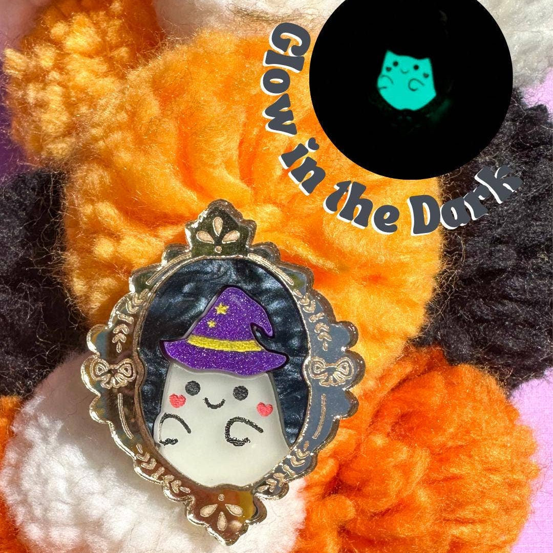 Ghost in a witch hat with a purple bow on a colorful yarn background, labeled 'Glow in the Dark'.