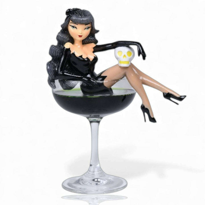 black widow woman in a black dress sitting on a wine glass with a skull in a cocktail. miss fluff december diamonds