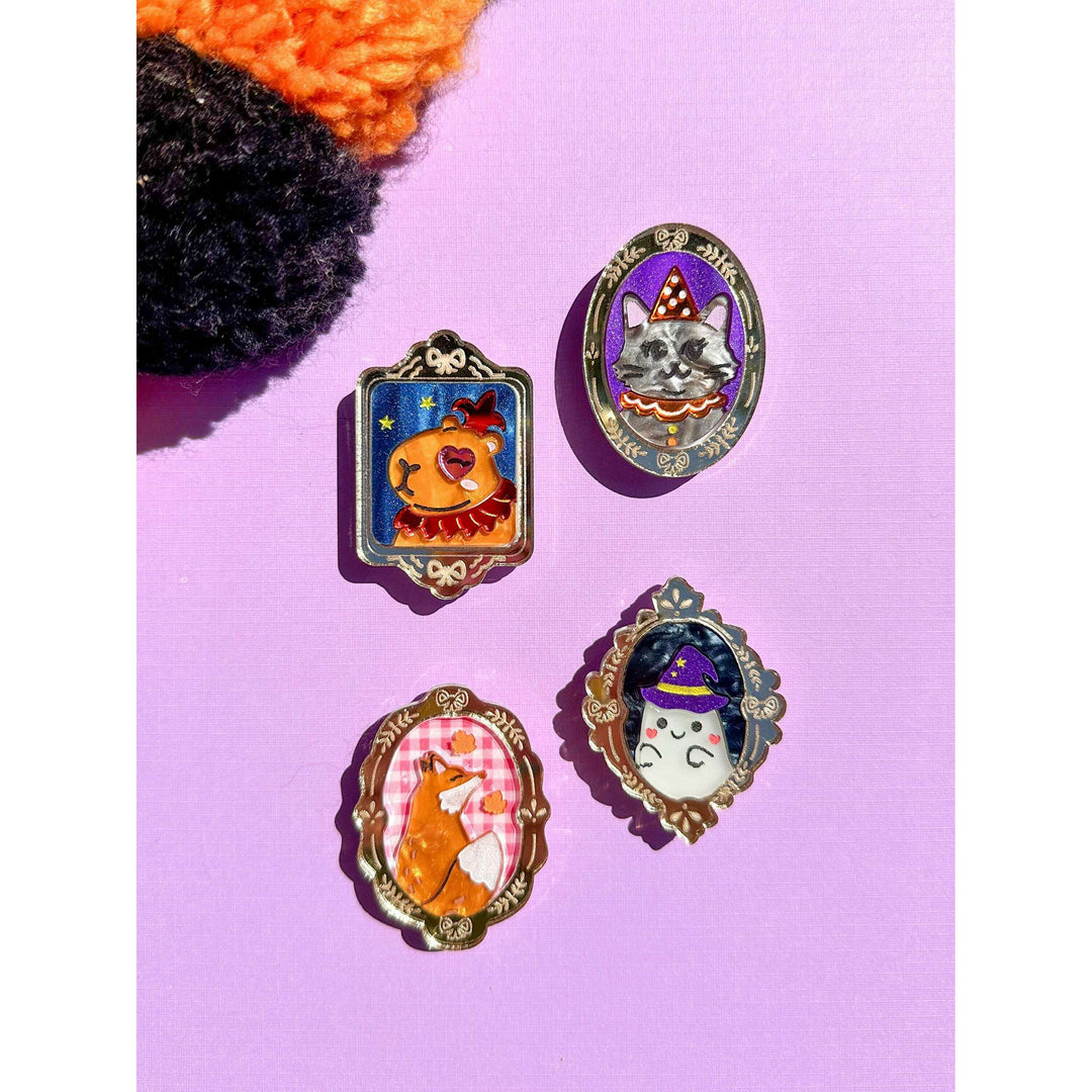 Four colorful pins with animal characters on a pink background