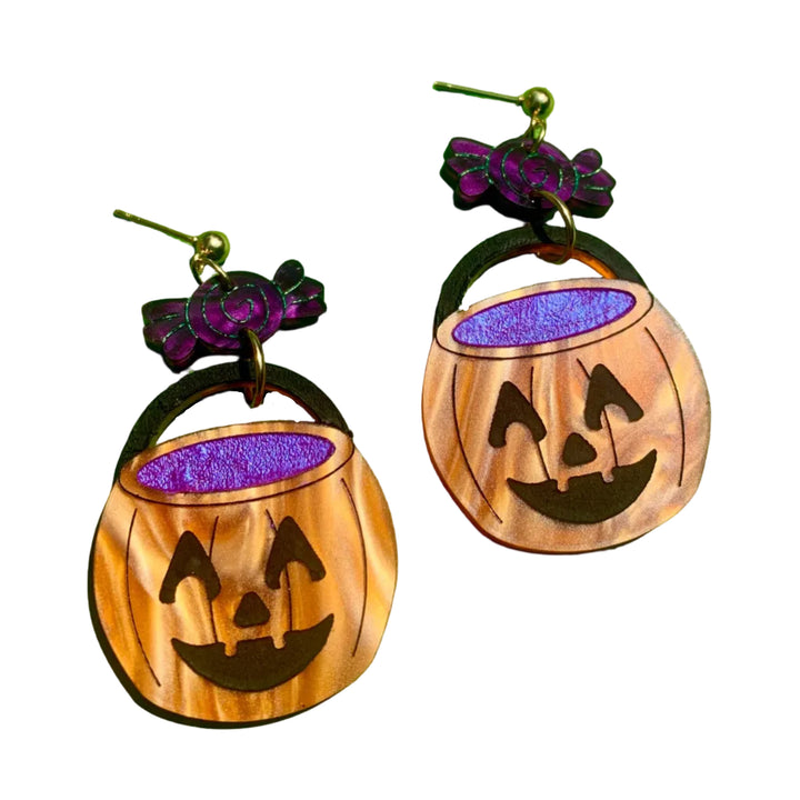 Halloween-themed earrings with purple glitter on a green background
