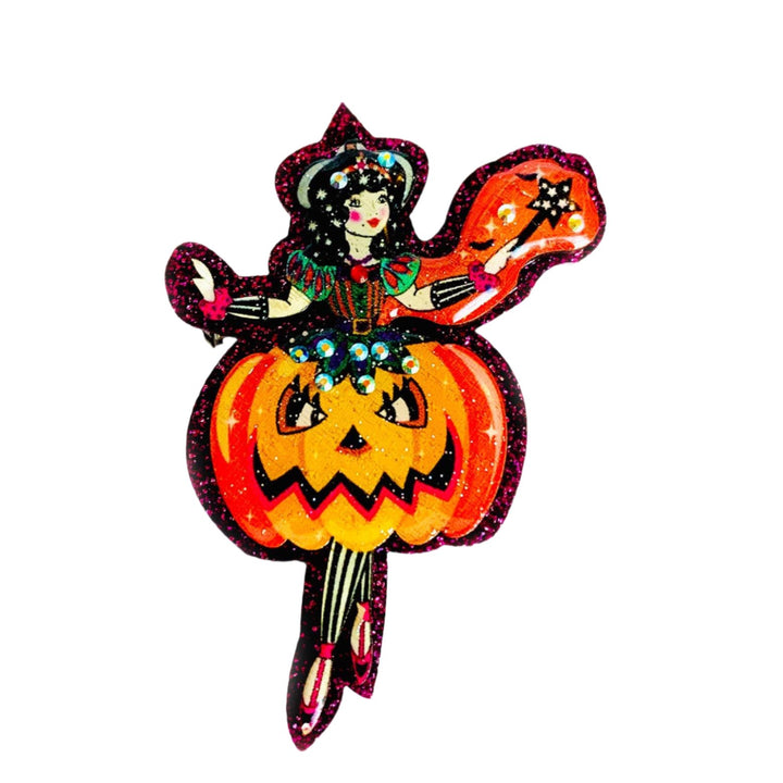 A decorative brooch featuring a fairy girl with a pumpkin costume, with a sparkle purple and multicolor design, resembling a Halloween-themed accessory.