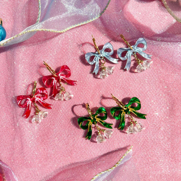 Colorful bow-shaped earrings on a pink fabric background