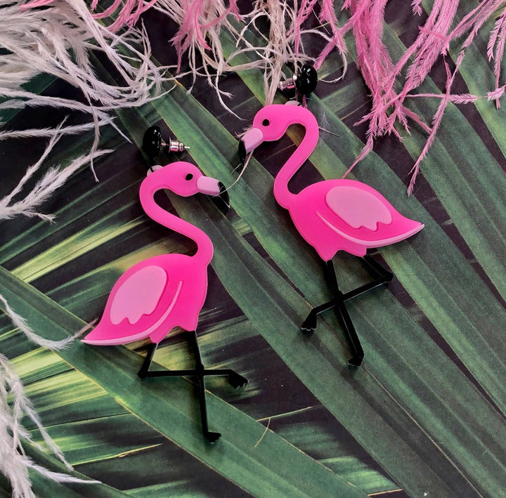 Pink flamingo earrings on a leafy background