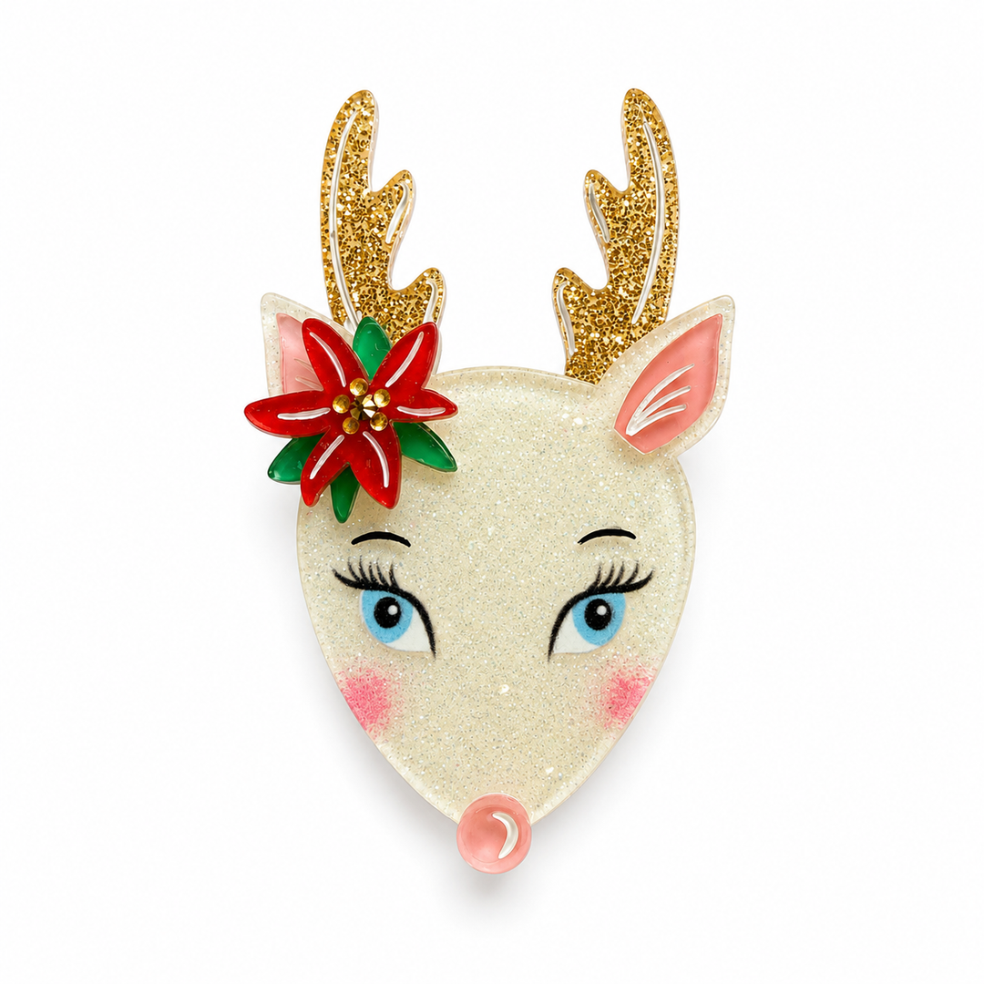 A festive Christmas reindeer head brooch or pin with a glittery cream face, gold glitter antlers, a red and green poinsettia flower on the side, blue eyes, pink inner ears and cheeks, and a small pink nose, shown on a plain white background.