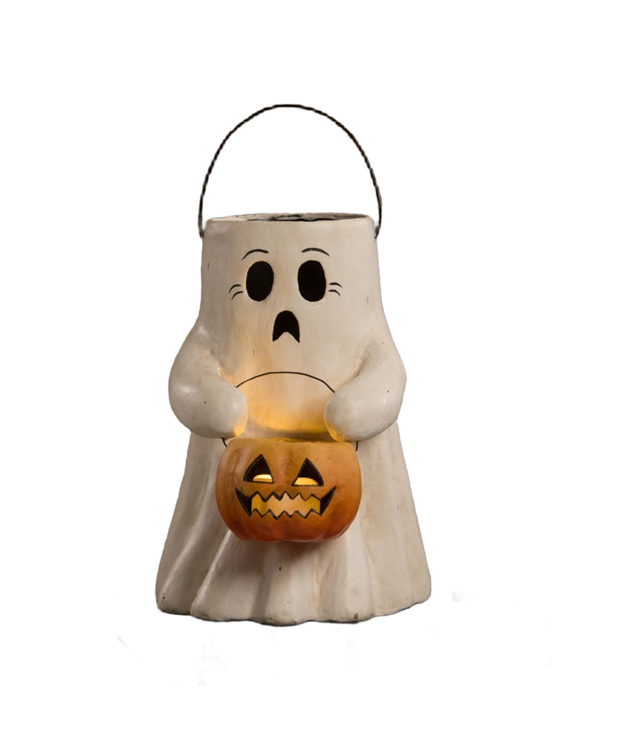 Ghost-shaped Halloween lantern holding a jack-o'-lantern on a wooden surface.