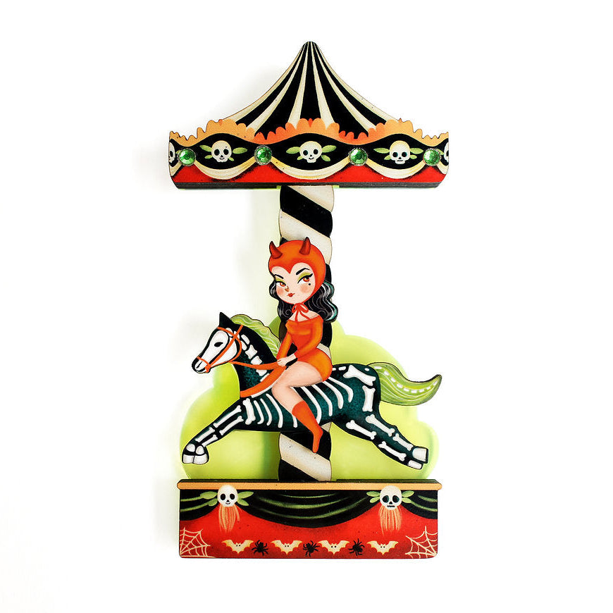 Decorative brooch with a woman riding a zebra on a carousel, featuring Halloween-themed elements.