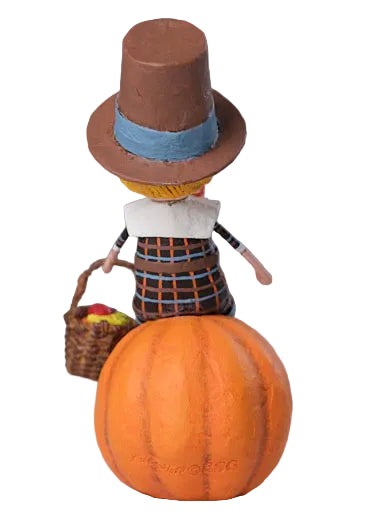 Decorative figure on a pumpkin with a brown hat and basket, against a neutral background