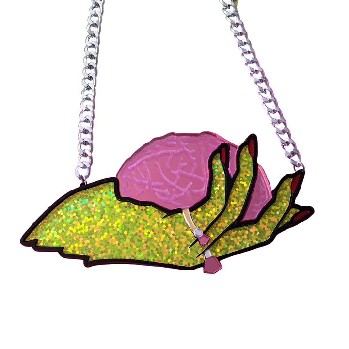 Neon green and pink floral pendant on a chain against a pink textured background